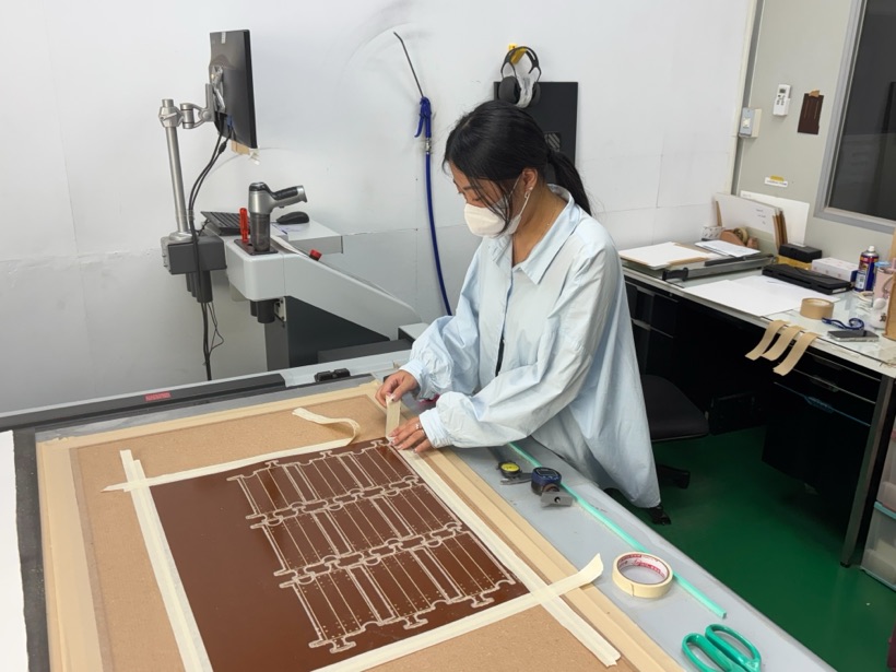 實習生在割樣機台上固定材料,準備割樣